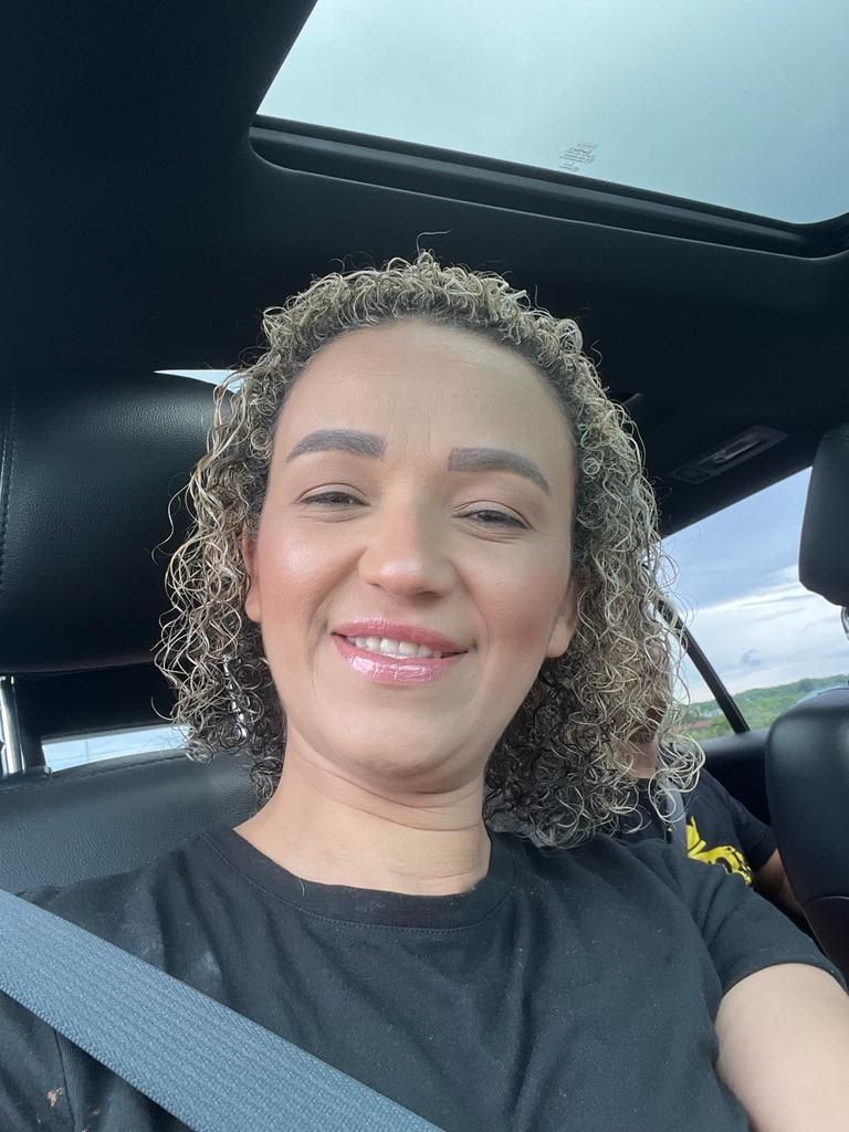 Person smiling while sitting in a car with a seatbelt on and sunroof overhead.